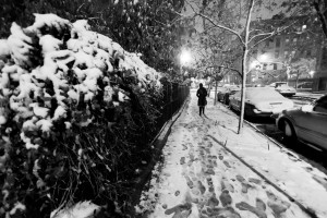 Lone woman walking on the snow covered pavement of a Harlem stre